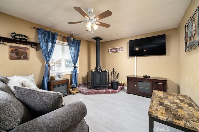 living room featuring ceiling fan and a wood stove