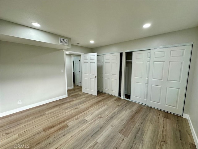 unfurnished bedroom with light hardwood / wood-style flooring and multiple closets