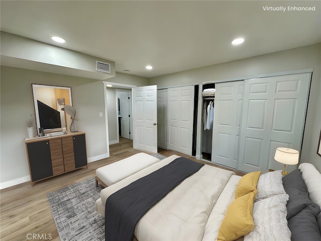 bedroom with light hardwood / wood-style flooring and two closets