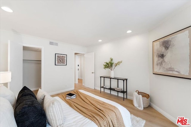 bedroom with crown molding, light hardwood / wood-style floors, and a closet