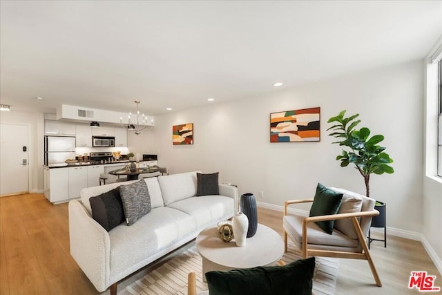 living room featuring a chandelier and light hardwood / wood-style flooring