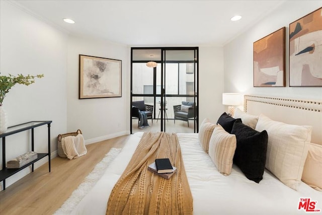 bedroom featuring a wall of windows, ornamental molding, and light wood-type flooring