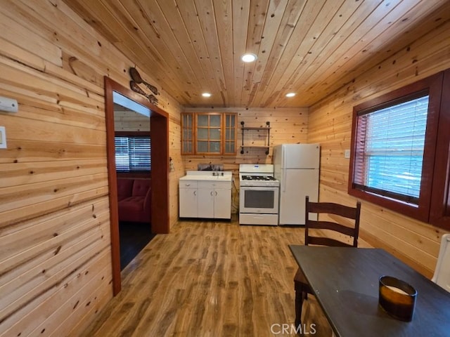 kitchen featuring white appliances, wooden walls, light countertops, light wood finished floors, and wooden ceiling