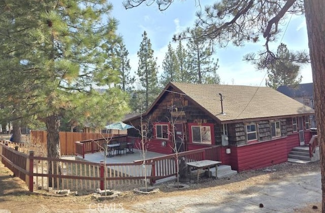 rear view of house featuring roof with shingles and fence