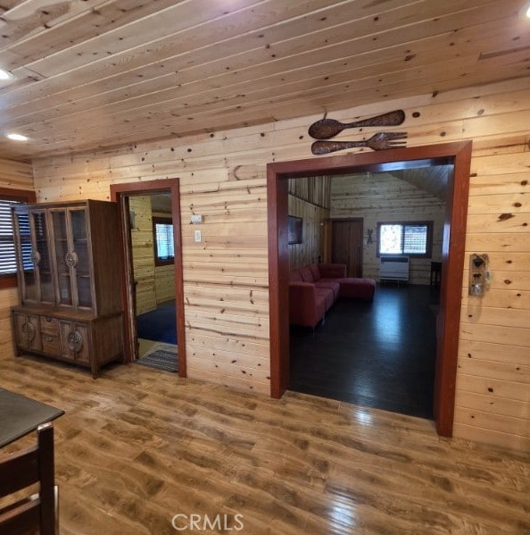 hall featuring wooden walls, wooden ceiling, and wood finished floors