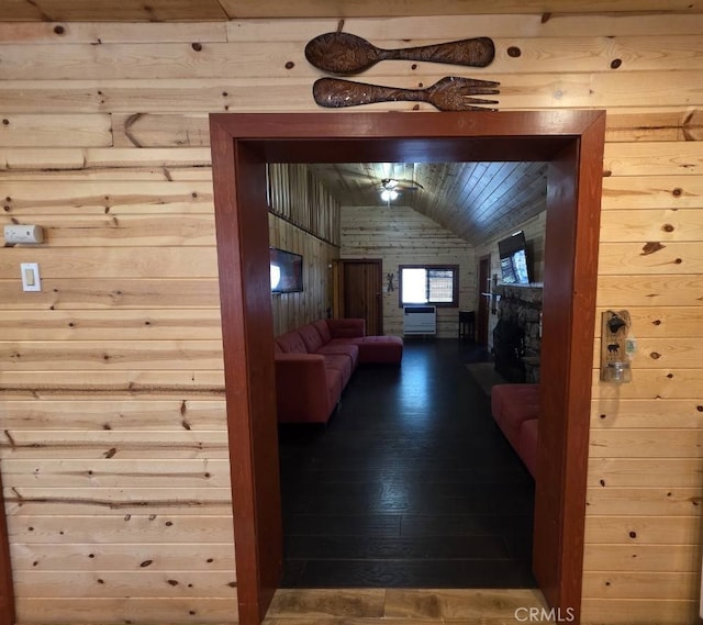 hall featuring dark wood finished floors, wooden walls, and lofted ceiling