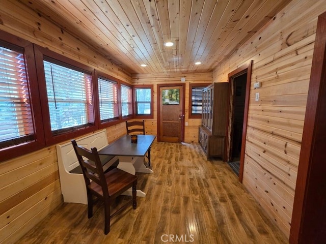 dining space with wooden walls, recessed lighting, wooden ceiling, and wood finished floors