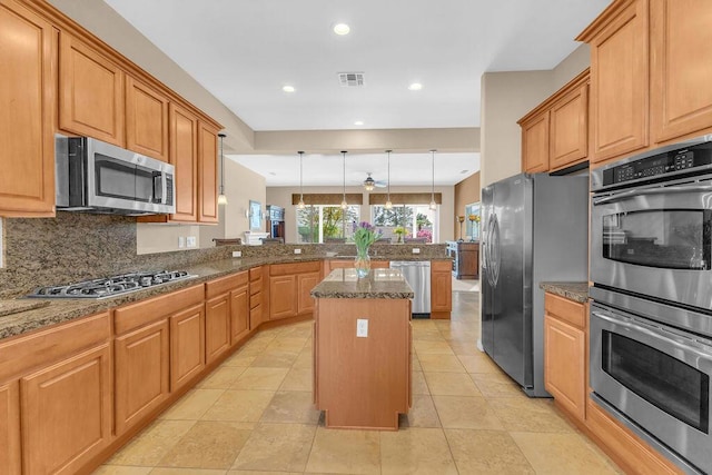 kitchen with a center island, appliances with stainless steel finishes, kitchen peninsula, pendant lighting, and backsplash