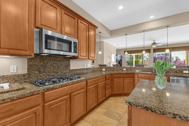 kitchen with ceiling fan, decorative backsplash, stainless steel appliances, and hanging light fixtures