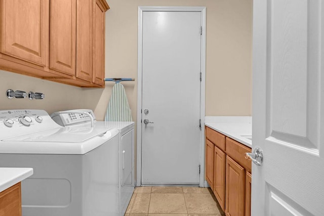 laundry room featuring washer and clothes dryer, cabinets, and light tile patterned flooring