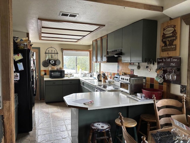 kitchen featuring a kitchen bar, sink, black appliances, kitchen peninsula, and backsplash