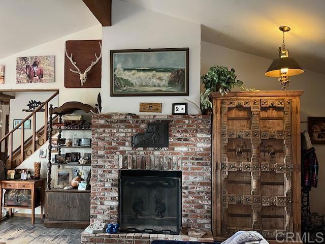 living room featuring lofted ceiling with beams, wood-type flooring, and a fireplace