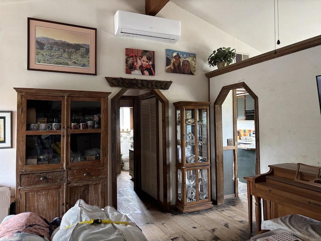 dining space with lofted ceiling, a wall mounted AC, and light hardwood / wood-style floors