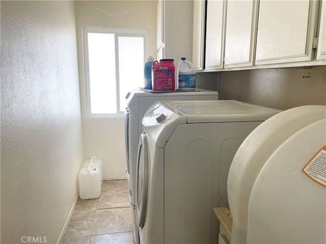 washroom featuring cabinet space, baseboards, washer and dryer, and light tile patterned flooring