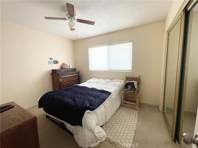 bedroom with light carpet, a closet, a ceiling fan, and baseboards