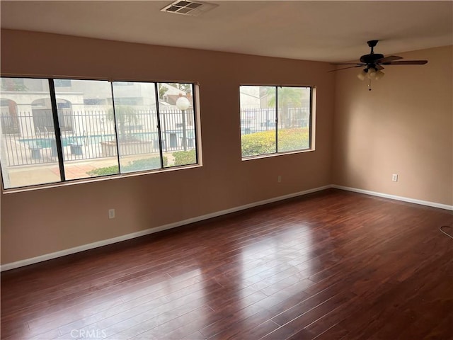 empty room with dark hardwood / wood-style floors and ceiling fan