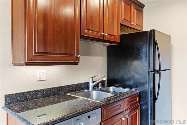 kitchen with black refrigerator, dishwashing machine, sink, and dark stone countertops