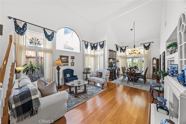 living room with wood-type flooring, an inviting chandelier, and high vaulted ceiling