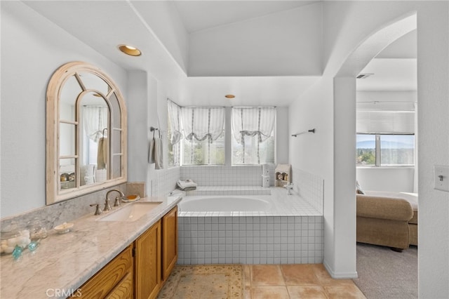 bathroom featuring a relaxing tiled tub, vanity, and tile patterned flooring