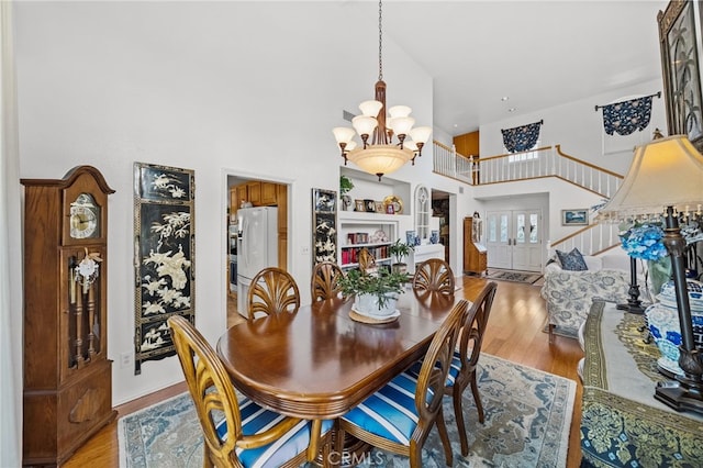 dining space with a towering ceiling, light hardwood / wood-style floors, and a chandelier