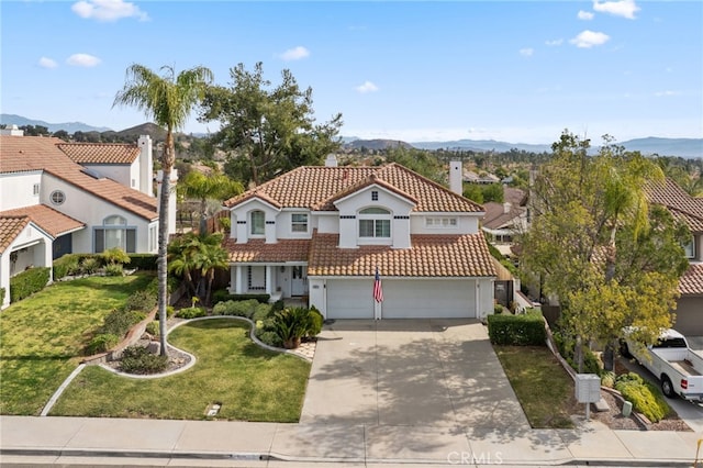 mediterranean / spanish-style home with a mountain view, a garage, and a front lawn