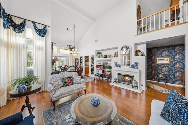 living room with hardwood / wood-style flooring, a chandelier, and high vaulted ceiling