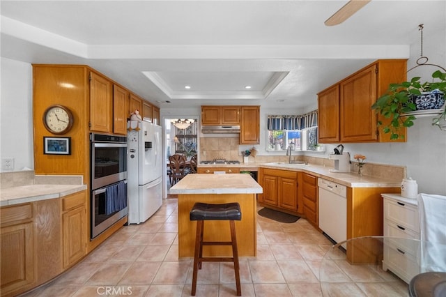 kitchen featuring a kitchen island, a breakfast bar, a raised ceiling, sink, and stainless steel appliances