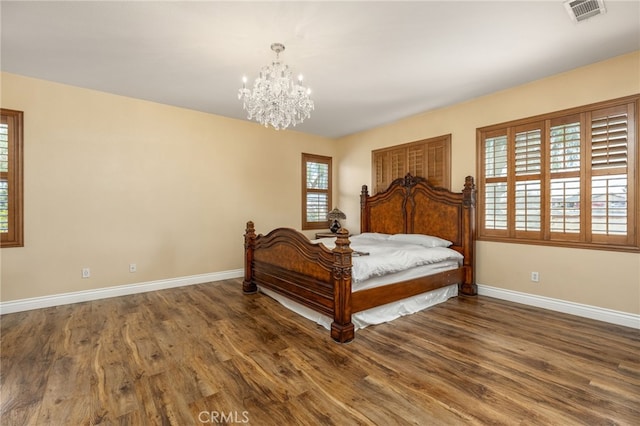 bedroom with dark hardwood / wood-style flooring and an inviting chandelier