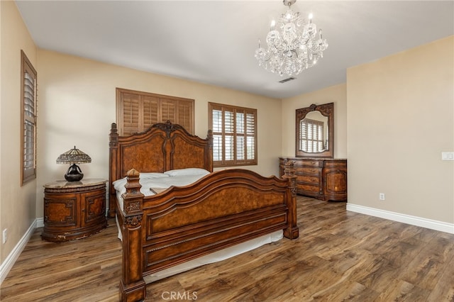 bedroom with hardwood / wood-style floors and an inviting chandelier