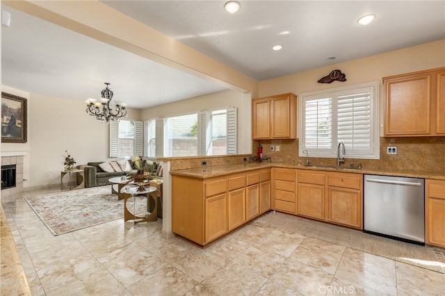 kitchen with sink, plenty of natural light, dishwasher, kitchen peninsula, and a tile fireplace