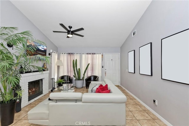 living room with a brick fireplace, vaulted ceiling, ceiling fan, and light tile patterned flooring