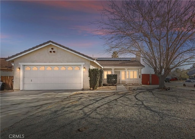 ranch-style home with a garage and solar panels