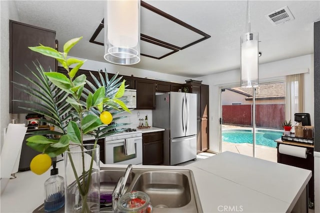 kitchen with hanging light fixtures, dark brown cabinets, and white appliances