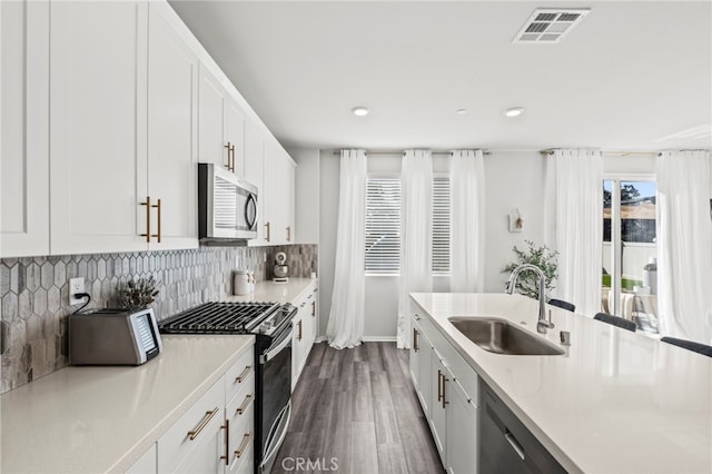 kitchen with dark wood-type flooring, sink, tasteful backsplash, appliances with stainless steel finishes, and white cabinets