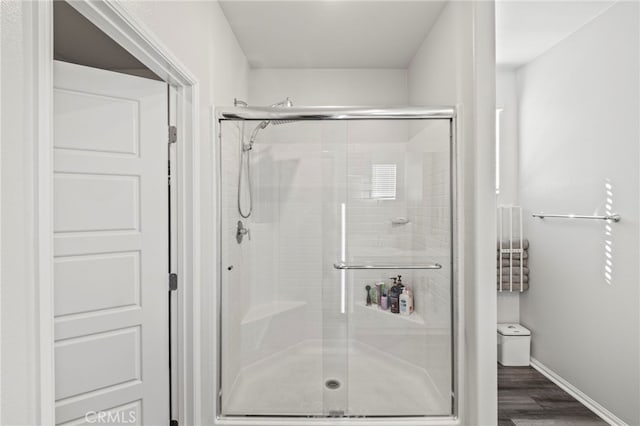 bathroom with a shower with door and hardwood / wood-style floors