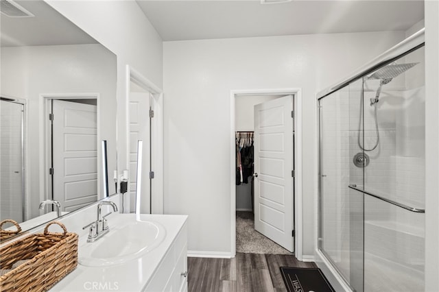 bathroom with hardwood / wood-style flooring, vanity, and a shower with shower door