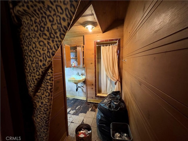 hall featuring wood-type flooring, wooden walls, and sink