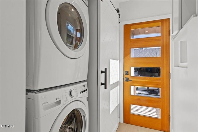 laundry room with stacked washer and clothes dryer and a barn door