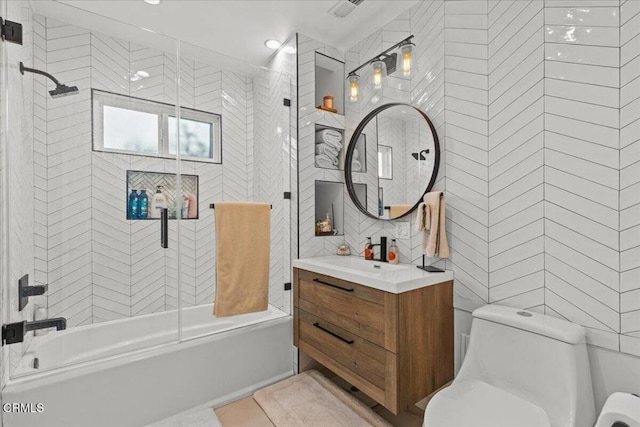 full bathroom with tile walls, vanity, toilet, and tiled shower / bath