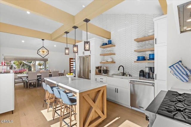 kitchen featuring pendant lighting, sink, a kitchen breakfast bar, white cabinets, and stainless steel dishwasher