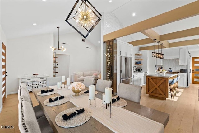 dining area featuring beam ceiling, high vaulted ceiling, a chandelier, and light wood-type flooring