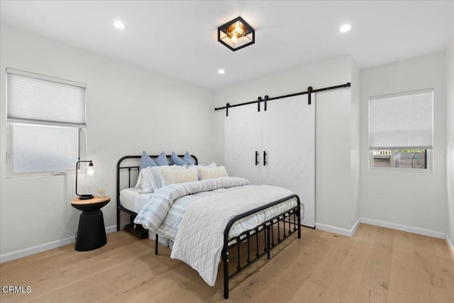 bedroom with a barn door and light wood-type flooring