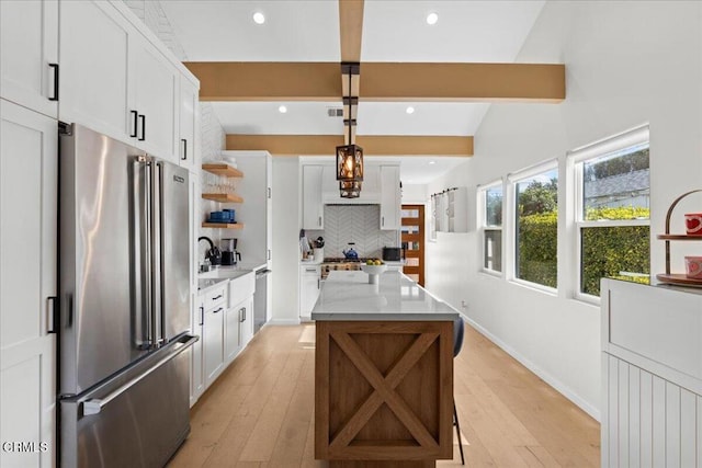 kitchen with high end fridge, decorative light fixtures, beamed ceiling, and white cabinets