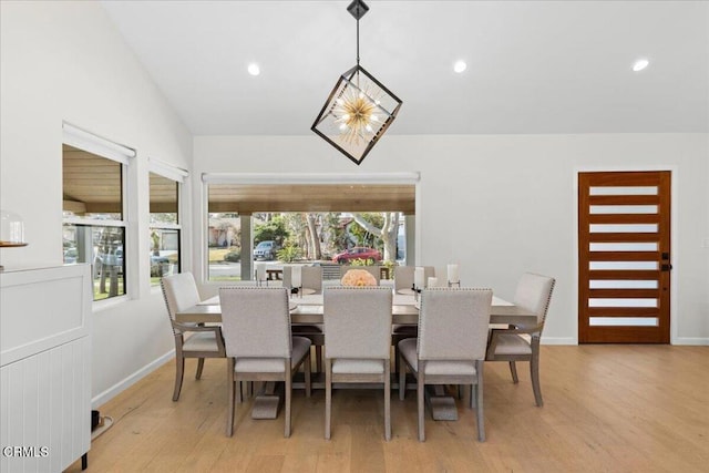 dining room with an inviting chandelier, vaulted ceiling, and light hardwood / wood-style flooring