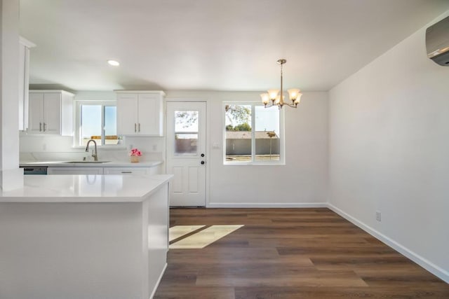 kitchen featuring an AC wall unit, sink, a wealth of natural light, and white cabinets