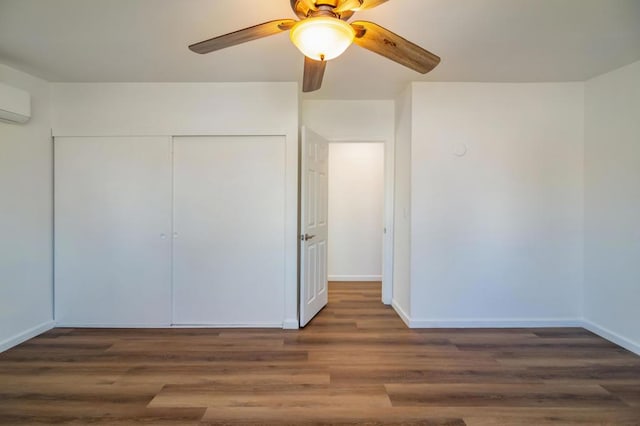 unfurnished bedroom with dark hardwood / wood-style flooring, ceiling fan, a closet, and a wall mounted AC