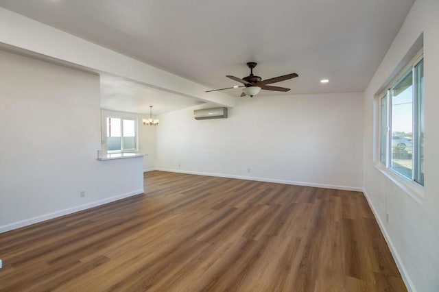 empty room featuring dark hardwood / wood-style floors, ceiling fan with notable chandelier, and a wall unit AC