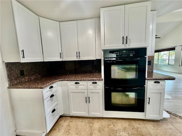 kitchen featuring white cabinetry, black double oven, and dark stone countertops