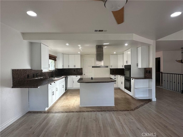 kitchen with sink, white cabinets, island exhaust hood, a center island, and black appliances