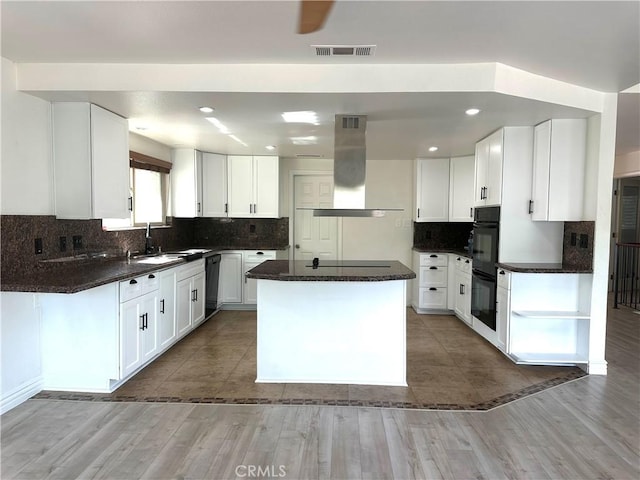 kitchen featuring a sink, island exhaust hood, backsplash, and black appliances